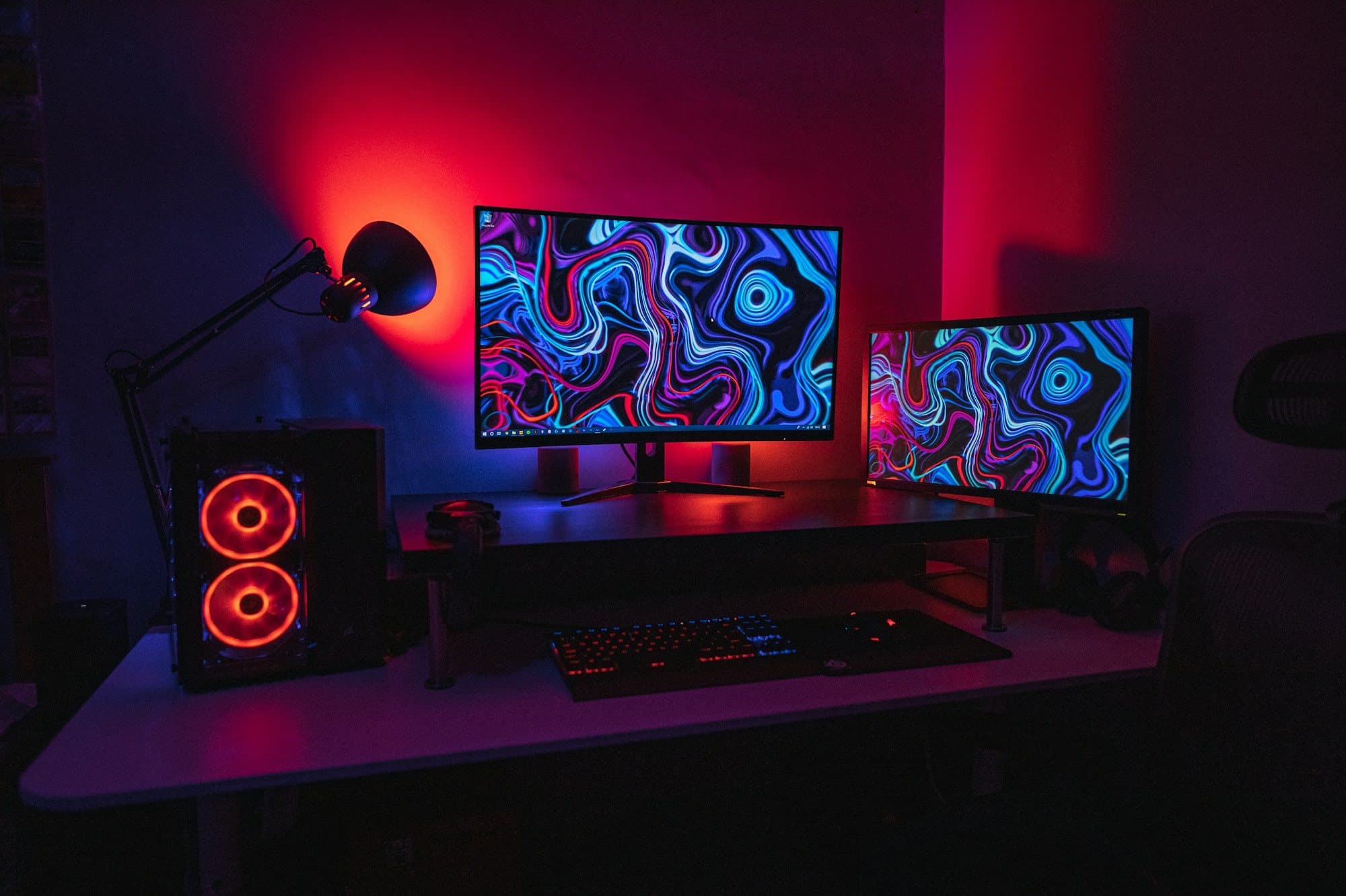 Dark desk setup with dual monitors, mechanical keyboard and red-lit tower